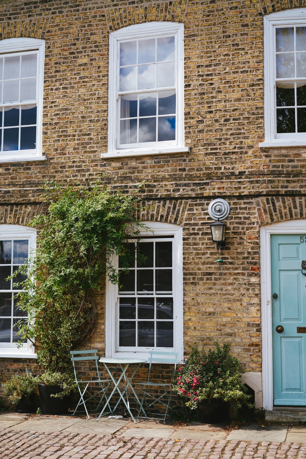 Period red-brick house with white painted sash windows and climbing plant